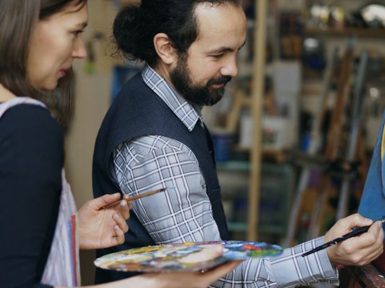 Deux personnes peignant ensemble sur une toile en atelier
